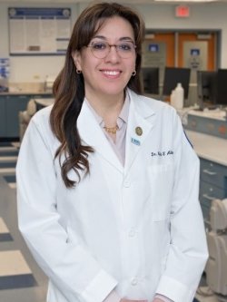 Profile photo of Dr. Melisa Alabsy wearing a white coat in the dental simulation lab.